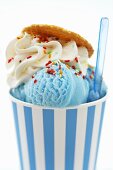 Blue ice cream in tub with sprinkles and plastic spoon