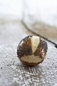 A lye bread roll with poppyseeds on a wooden surface