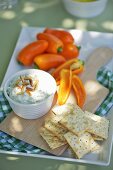 Cream cheese and rocket dip with pine nuts, crakers and peppers