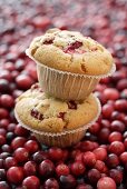 Two cranberry muffins, one on top of the other on cranberries