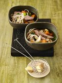 Vegetable noodle soup with veal fillet in two bowls