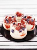 Four glasses of yoghurt with raspberries, blueberries & chocolate