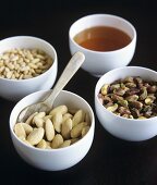 Pine nuts, almonds, pistachios and honey in small bowls