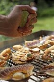 Sprinkling seafood on a barbecue with lemon juice