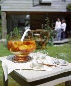 Pfirsichbowle mit Gläsern auf einem Gartentisch