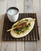 Mince kebab on lemon grass skewer with pea salad on bread