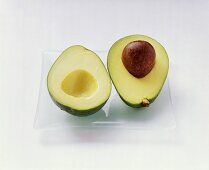 A halved avocado on a glass plate