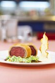 Saddle of venison wrapped in bread with cream savoy cabbage and celery chips