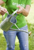 A woman with a watering can in a garden