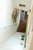 A white wooden staircase with a view of a parquet floor