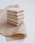 A stack of ham and cheese sandwiches on a paper napkin