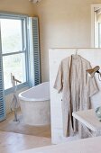 Badezimmer in beige mit Badewanne unter Fenster mit blauen Sonnenschutz von Innen