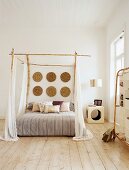 Ein Himmelbett mit Bambusstäbe und weiße Vorhänge im Schlafzimmer