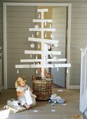 A girl opening presents in front of a wooden Christmas tree