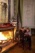 A grandpa and his granddaughter in front of a fire