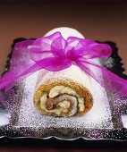 Poppy seed and cinnamon sponge roulade with icing sugar and pink bow