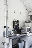 Eine zweckmäßige Küchenzeile mit Spülbecken und Elektrogeräten vor einer weissen Backsteinwand