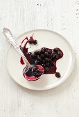 A blob of chokeberry jam on a plate with a ladle