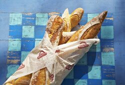 Baguettes in paper on a blue painted wooden surface