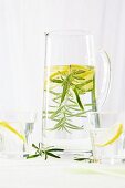 A jug of water with lemon slices and a rosemary sprig