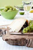 Parmesan cheese with grapes on a wooden board