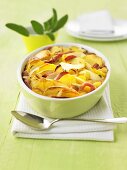 Potato and apple gratin with smoked pork in a baking dish