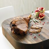 Partly carved leg of lamb with pomegranate seeds, chopping board