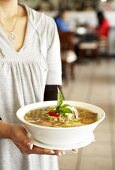 Woman carrying a bowl of pho (Beef and rice noodle soup)