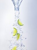Water and lime wedges pouring out of bottle