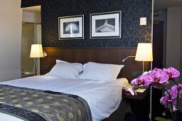 Stilvolles Hotelzimmer mit Doppelbett, Nachttischleuchten & Blumenschmuck (Paris, Frankreich)