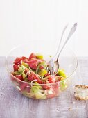 Tomato salad in glass bowl with salad servers