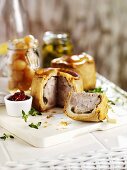 Pork pies (one with a piece cut), pickled onions & gherkins