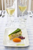 Piece of vegetable terrine with accompaniments and white wine