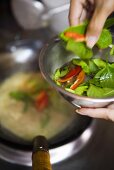 Seasoning food in wok with Thai basil and chillies (Thailand)