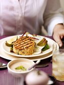 Woman sitting in front of plate of food (grilled fish cake)