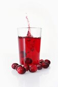 Ice cube falling into cranberry juice