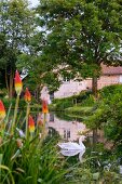 Swan in garden pond with romantic country house in background