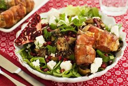 Salad with fresh goat's cheese, pomegranate and bacon rolls