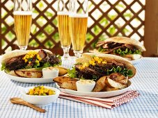 Pork sandwiches with mango salsa & potato wedges, glasses of beer