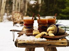 Heiße Kentucky Toddy Drinks und Plätzchen auf Tisch im verschneitem Garten