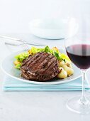 Rib eye steak with onions & romaine lettuce, glass of red wine