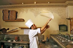 Italian pizza baker throwing dough into the air