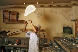 Italian pizza baker throwing dough into the air