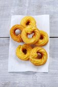 Deep-fried choux pastry rings on piece of kitchen roll