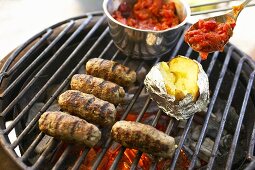 Cevapcici with baked potato and tomatoes on barbecue