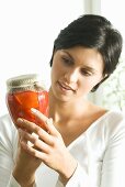 Young woman holding a jar of pickled peppers
