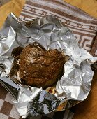 Fried steak resting in aluminium foil