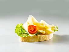 A slice of white bread topped with lettuce, cheese and tomato