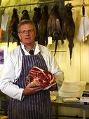 A butcher holding beef ribs in his hands at a Farmer's Market in England