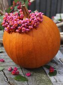 A giant pumpkin with a wreath of spindle flowers